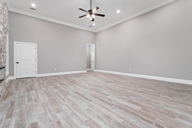 unfurnished room featuring ornamental molding, a towering ceiling, ceiling fan, and light wood-type flooring