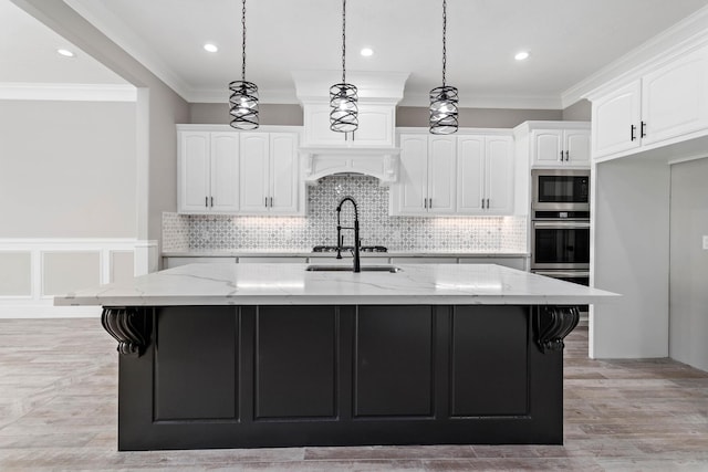 kitchen featuring white cabinetry, light stone countertops, and an island with sink