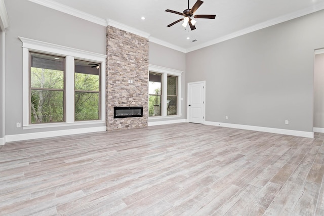 unfurnished living room featuring crown molding, ceiling fan, light wood-type flooring, and a wealth of natural light