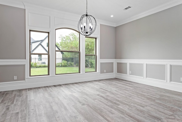 unfurnished dining area featuring crown molding, light hardwood / wood-style flooring, and a chandelier