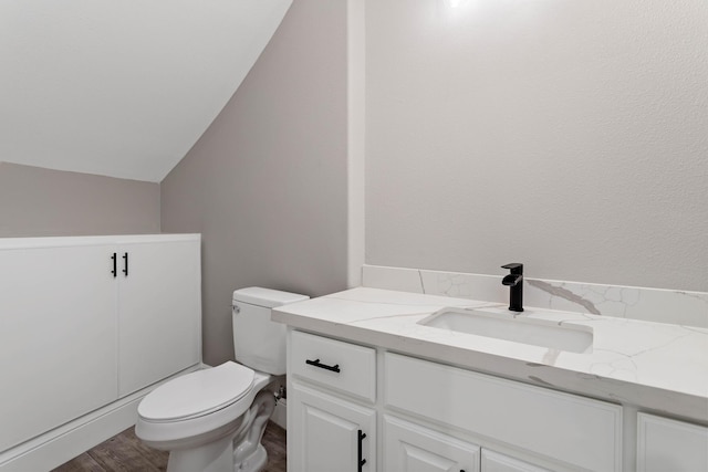 bathroom featuring lofted ceiling, vanity, toilet, and wood-type flooring