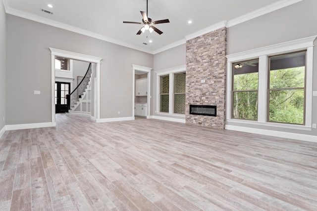 unfurnished living room featuring crown molding, ceiling fan, a fireplace, light hardwood / wood-style floors, and a high ceiling