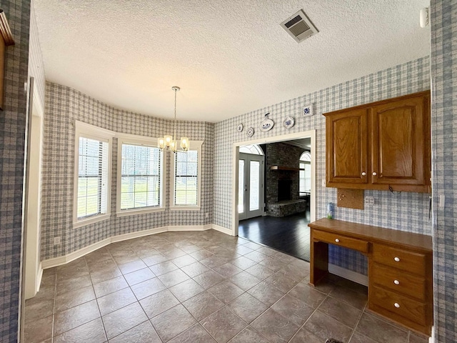 unfurnished dining area with a notable chandelier, visible vents, a textured ceiling, and wallpapered walls