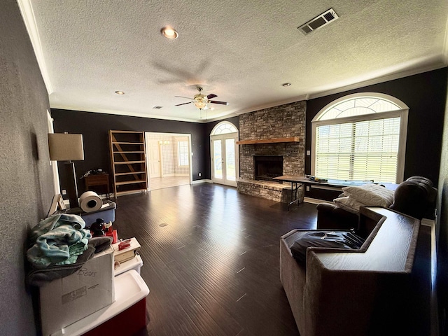 living room with visible vents, plenty of natural light, a stone fireplace, and wood finished floors