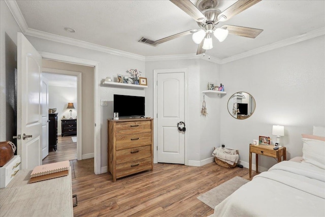 bedroom with crown molding, light wood finished floors, visible vents, a ceiling fan, and baseboards