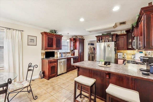 kitchen featuring reddish brown cabinets, visible vents, stainless steel appliances, and ornamental molding