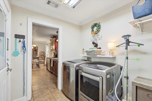 clothes washing area with crown molding, light tile patterned floors, visible vents, washing machine and dryer, and laundry area