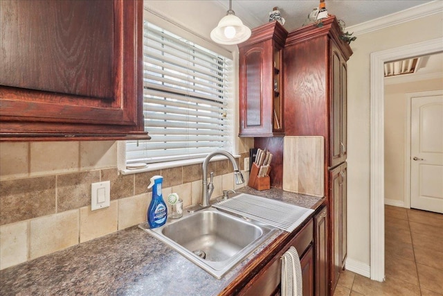 kitchen featuring crown molding, light tile patterned floors, dark countertops, a sink, and dark brown cabinets