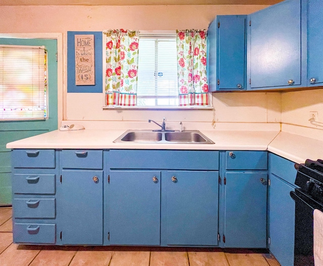 kitchen with black stove, blue cabinets, sink, and light tile patterned floors