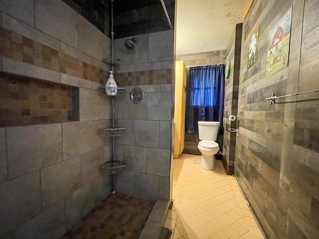 bathroom featuring tile patterned flooring, toilet, and tiled shower