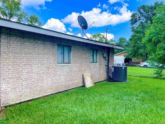 view of side of home featuring central air condition unit and a yard