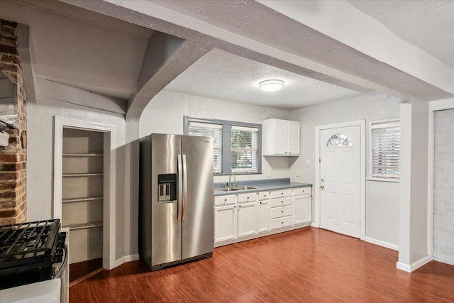 kitchen with white cabinets, stainless steel fridge with ice dispenser, dark hardwood / wood-style floors, and black gas stove