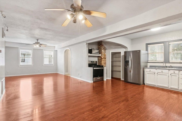 unfurnished living room featuring a textured ceiling, light wood-type flooring, ceiling fan, and sink