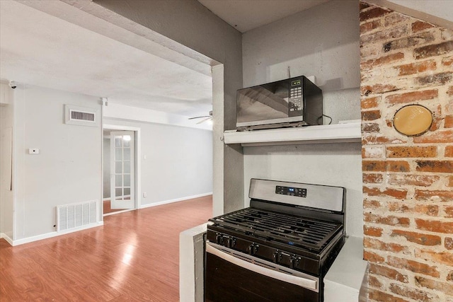 kitchen featuring gas range, ceiling fan, and wood-type flooring