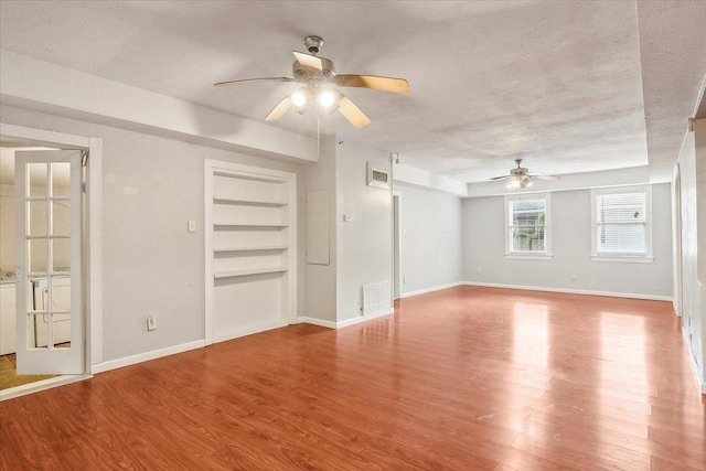 interior space with ceiling fan, built in features, a textured ceiling, and light hardwood / wood-style flooring