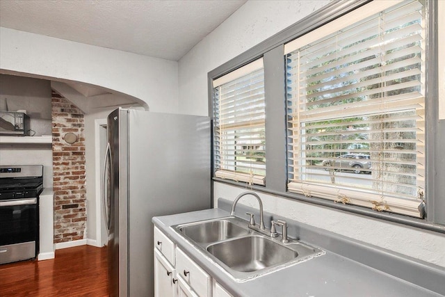 kitchen featuring appliances with stainless steel finishes, a textured ceiling, sink, white cabinets, and dark hardwood / wood-style floors