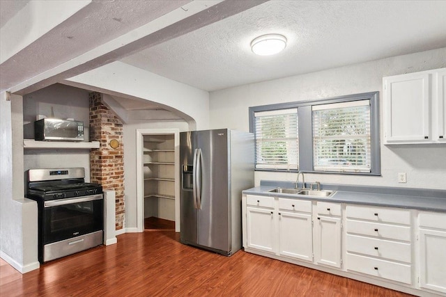 kitchen featuring a textured ceiling, stainless steel appliances, sink, hardwood / wood-style flooring, and white cabinetry