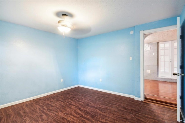 spare room with ceiling fan, dark wood-type flooring, and french doors