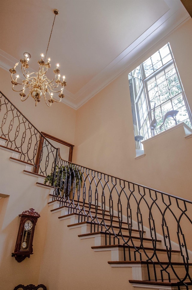 stairs featuring a chandelier, a towering ceiling, and crown molding