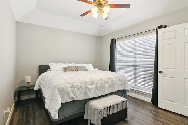 bedroom with a tray ceiling, ceiling fan, and dark wood-type flooring