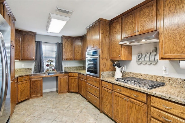 kitchen featuring light stone counters, light tile patterned floors, and stainless steel appliances