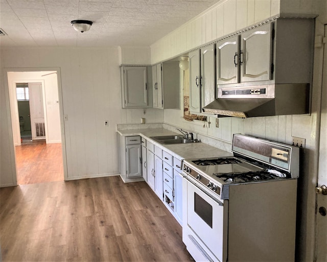 4701 Redbird St, Port Arthur, TX 77642 - kitchen featuring white gas range, a sink, wood finished floors, under cabinet range hood, and light countertops