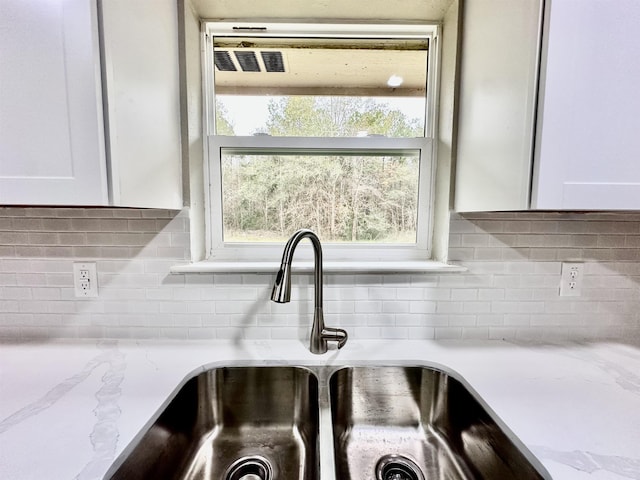 room details with light stone countertops, white cabinetry, and sink