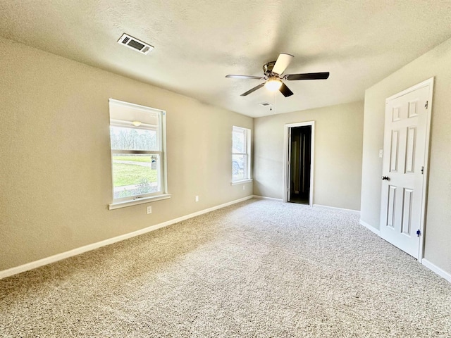 unfurnished bedroom featuring multiple windows, ceiling fan, carpet floors, and a textured ceiling