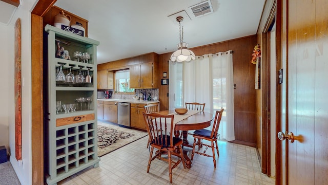 dining space with visible vents, light floors, and wooden walls