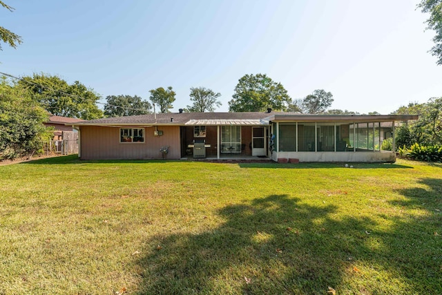 back of property with a lawn and a sunroom