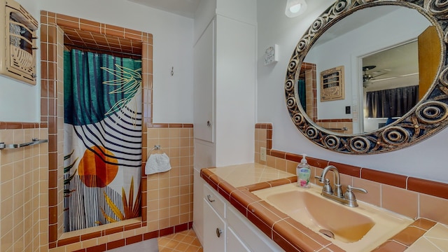 full bath featuring a wainscoted wall, a ceiling fan, a shower with shower curtain, tile walls, and vanity