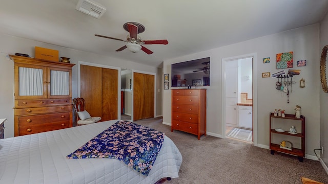 carpeted bedroom with baseboards, visible vents, ensuite bath, ceiling fan, and multiple closets