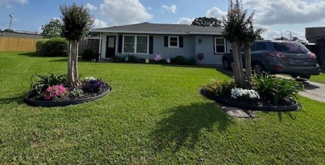 ranch-style home featuring a front lawn and fence