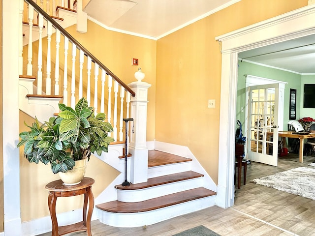 stairs with hardwood / wood-style floors, crown molding, and french doors