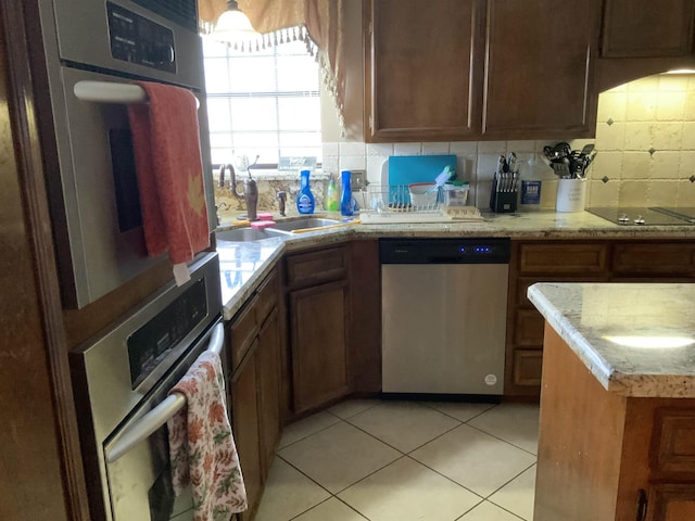 kitchen featuring light tile patterned floors, tasteful backsplash, stainless steel dishwasher, and sink