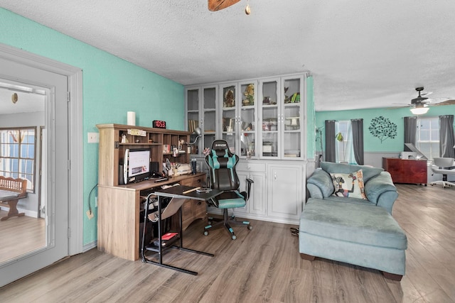 office area with a textured ceiling, wood finished floors, and a ceiling fan