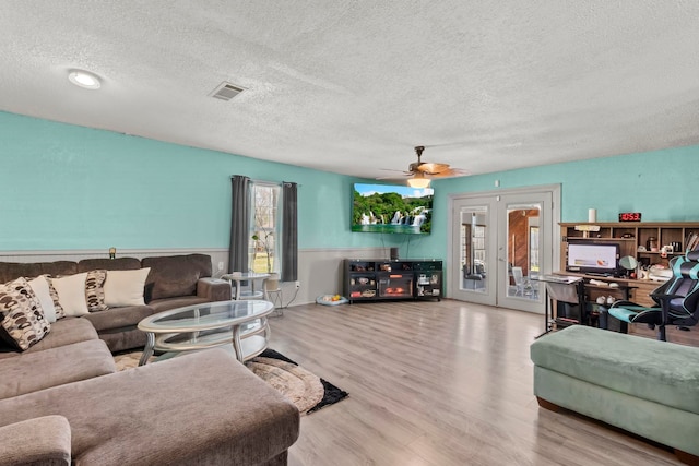 living area featuring a textured ceiling, french doors, wood finished floors, and visible vents