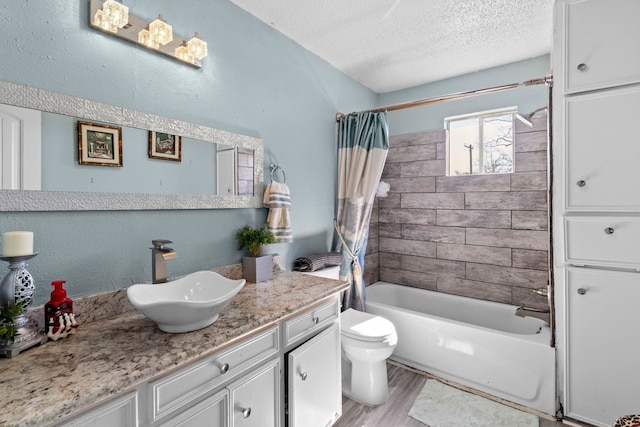 bathroom featuring toilet, shower / bath combo with shower curtain, vanity, a textured ceiling, and wood finished floors