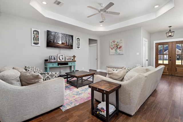 living room with ceiling fan, dark hardwood / wood-style floors, and a raised ceiling