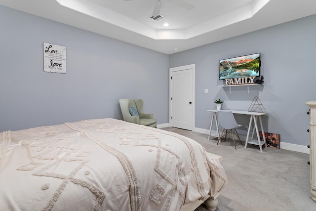 carpeted bedroom featuring ceiling fan and a tray ceiling