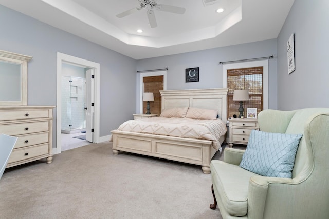 carpeted bedroom featuring connected bathroom, a tray ceiling, and ceiling fan