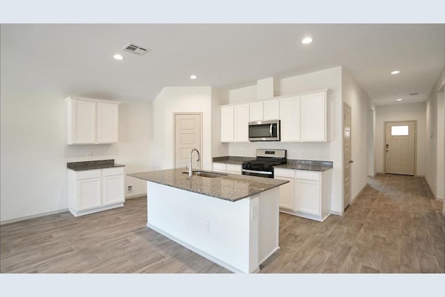 kitchen with white cabinetry, sink, stainless steel appliances, light hardwood / wood-style flooring, and an island with sink