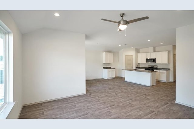 kitchen featuring white cabinetry, ceiling fan, stainless steel appliances, light hardwood / wood-style floors, and a center island with sink