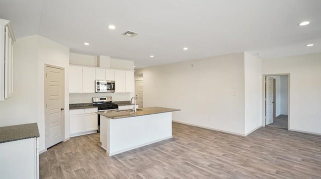 kitchen with sink, an island with sink, light hardwood / wood-style floors, white cabinets, and appliances with stainless steel finishes