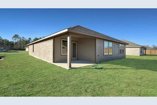 back of house with a patio area and a lawn