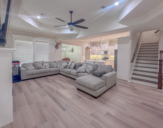 308 Long Leaf St, Silsbee, TX 77656 - living area with ceiling fan, light wood-type flooring, a tray ceiling, stairway, and arched walkways