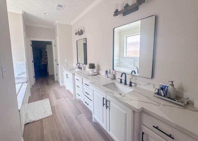308 Long Leaf St, Silsbee, TX 77656 - full bathroom featuring ornamental molding, double vanity, a bath, wood finished floors, and a textured ceiling