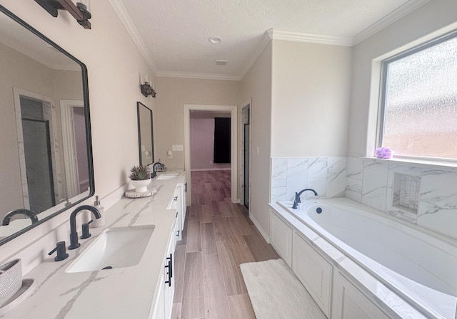 308 Long Leaf St, Silsbee, TX 77656 - full bath featuring wood finished floors, a garden tub, double vanity, ornamental molding, and a textured ceiling