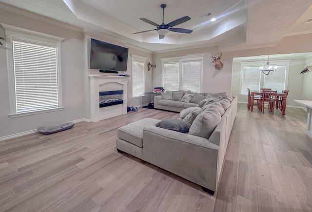 308 Long Leaf St, Silsbee, TX 77656 - living room with a tray ceiling, a ceiling fan, a chandelier, light wood-style floors, and ornamental molding