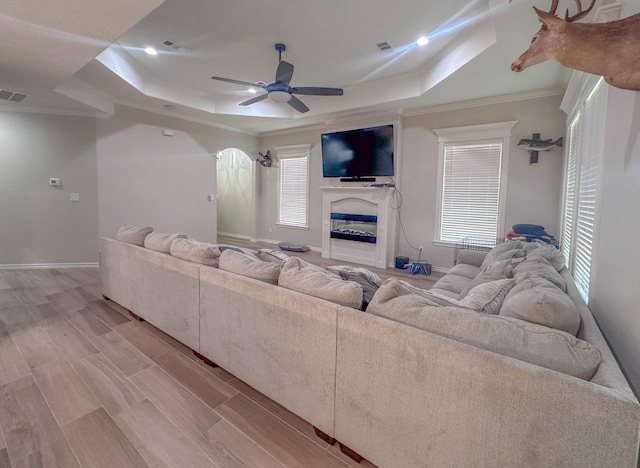 308 Long Leaf St, Silsbee, TX 77656 - living area with a tray ceiling, ceiling fan, ornamental molding, light wood finished floors, and a glass covered fireplace
